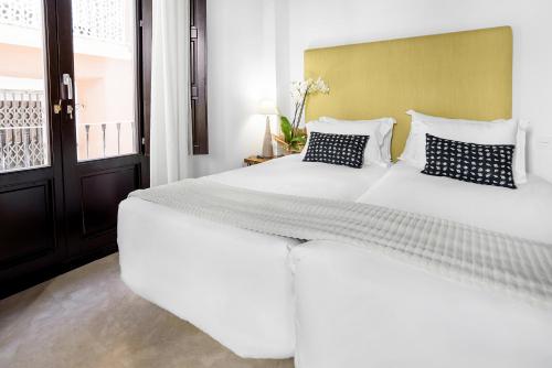 a large white bed in a room with a window at Suites Campo del Príncipe by Maxi Hoteles in Granada