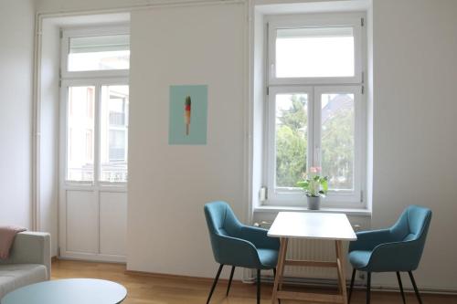a living room with two chairs and a table and two windows at Apartment Two am Stadtpark in Villach