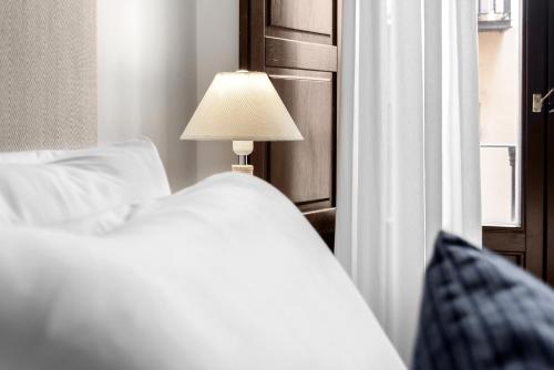 a bedroom with a bed and a lamp next to a window at Suites Campo del Príncipe by Maxi Hoteles in Granada