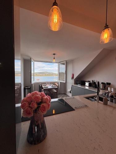 a vase of roses on a counter in a kitchen at Stylish Coastal Apartment with Breathtaking views in Conwy