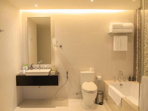 a bathroom with a sink and a toilet and a mirror at The Costa Nha Trang Residences in Nha Trang