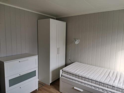 a small bedroom with a bed and a white cabinet at Room with shared kitchen and bathroom nr 3 in Tromsø