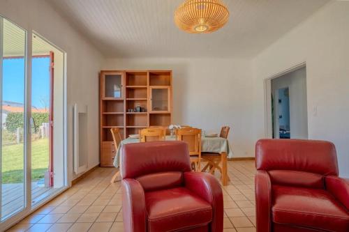 a living room with red chairs and a table at Maison Caupos in Biscarrosse