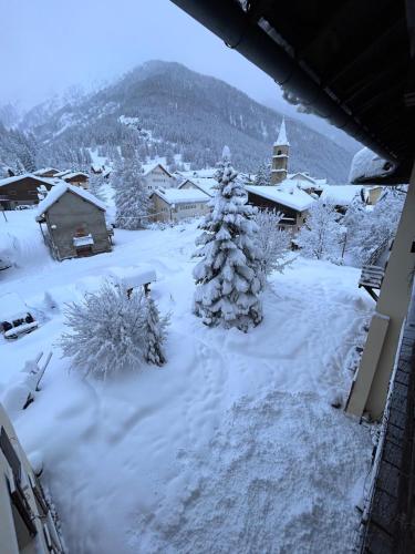 a snow covered town with a christmas tree in the yard at Le Ristolas in Ristolas