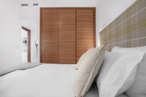 a bedroom with a large bed with white pillows at Suites Campo del Príncipe by Maxi Hoteles in Granada