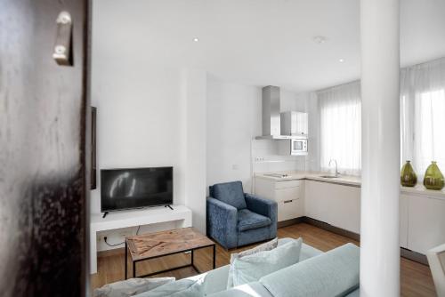 a living room with a blue chair and a television at Suites Campo del Príncipe by Maxi Hoteles in Granada