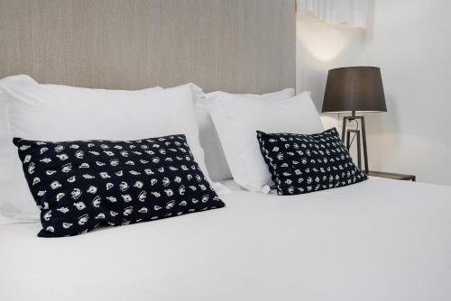 a white bed with black and white pillows at Suites Campo del Príncipe by Maxi Hoteles in Granada