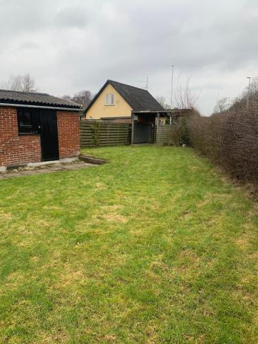 a yard with a brick house and a building at Townhouse centrally located close to Jesperhus in Nykøbing Mors