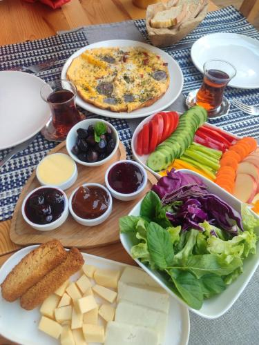 a table with plates of cheese and vegetables and a pizza at TasEV Guesthouse in North Nicosia