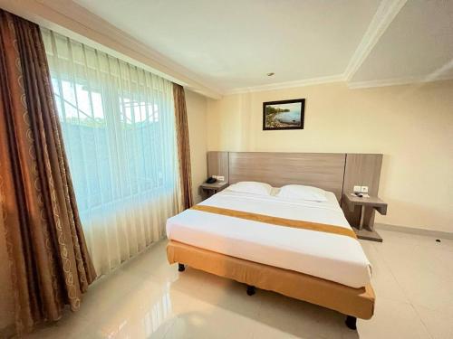 a bedroom with a large bed and a large window at Manise Hotel in Ambon