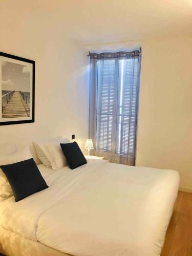 une chambre avec un grand lit blanc avec une fenêtre dans l'établissement Cannes Serenity – Elegant Stay in Central Cannes, à Cannes