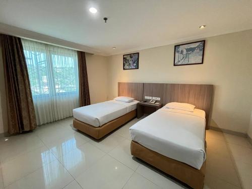 a hotel room with two beds and a window at Manise Hotel in Ambon