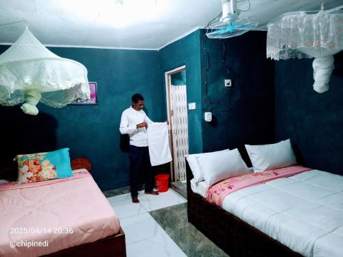 a man is standing in a room with two beds at Mount Mulanje Stopover in Peremwe