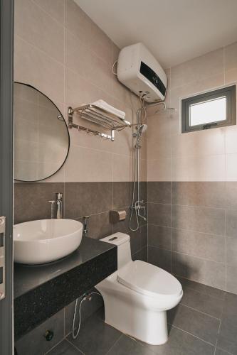a bathroom with a toilet and a sink and a mirror at Nhà Nhím in Da Lat