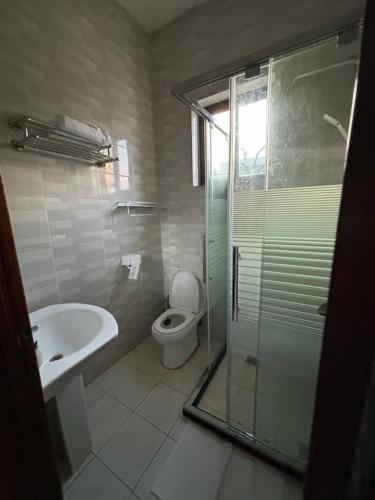 a bathroom with a shower and a toilet and a sink at ISARO Estate in Kigali
