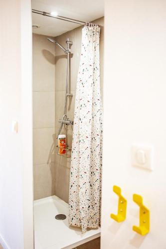 un rideau de douche dans une salle de bain avec des chaussures jaunes dans l'établissement Farigoule Appartement rénové avec balcon, à Martigues