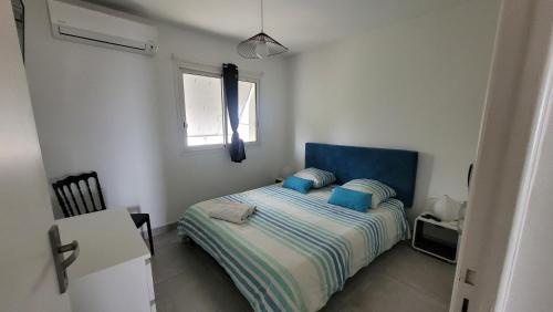 - une chambre avec un lit doté d'une tête de lit bleue et d'une fenêtre dans l'établissement Superbe appartement vue mer - 2 chambres - parking, à Palavas-les-Flots