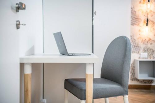 a laptop computer sitting on a white table with a chair at Casa Amelia Elegant Suite parcheggio gratuito in Parma