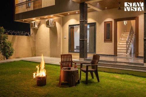 two chairs and a table and a fire pit in a yard at StayVista at The Binclave with Jacuzzi, Pvt Indoor Pool, Bar & Projector in Jaipur