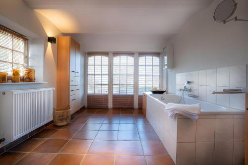 a bathroom with a tub and a large window at Landhaus Sommerland in Uelvesbüll