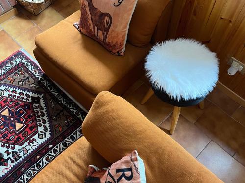 ein Wohnzimmer mit zwei Stühlen und einem weißen Ottomanen in der Unterkunft Tree House in Camigliatello Silano