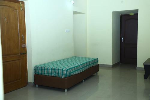a small bed in a room next to a door at Shiva Nest in Tiruchchirāppalli