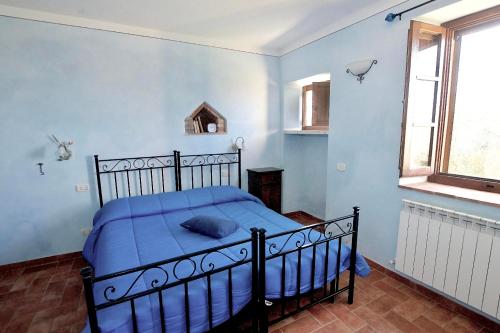 a bedroom with a bed with blue walls and a window at Agriturismo Caliano in Asciano