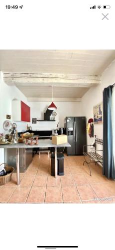 une cuisine avec une table et un réfrigérateur dans l'établissement La forge, à Laroque-de-Fa