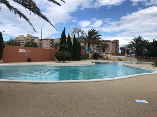 une piscine dans un parc avec des arbres et des bâtiments dans l'établissement Farniente, à Canet
