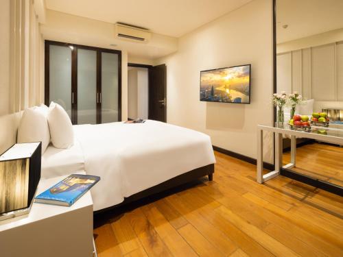 a hotel room with a white bed and a table at The Costa Nha Trang Residences in Nha Trang