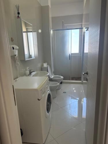 a white bathroom with a toilet and a sink at Nuna Hotel & Apartments in Vlorë