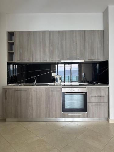 a kitchen with wooden cabinets and a stove top oven at Nuna Hotel & Apartments in Vlorë