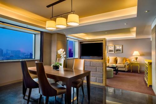 a dining room with a table and a television at Sofitel Zhengzhou International in Zhengzhou