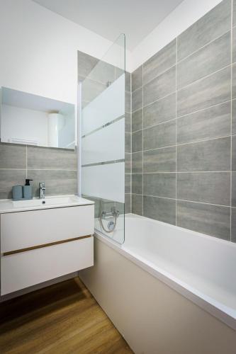 une salle de bain avec une baignoire, un lavabo et un miroir dans l'établissement Confortable studio 2 Pers wifi, à Saint-Quentin