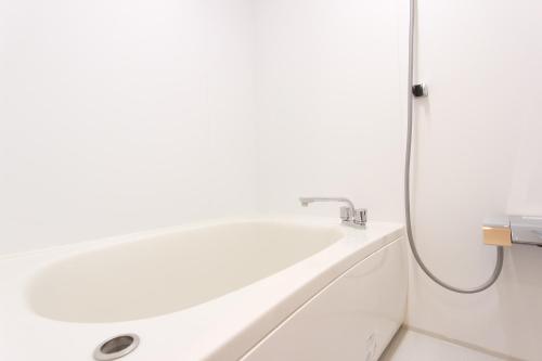 a white bath tub in a bathroom with a shower at HOTEL DO-YA Beppu in Beppu