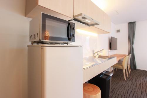 a kitchen with a refrigerator with a microwave at HOTEL DO-YA Beppu in Beppu