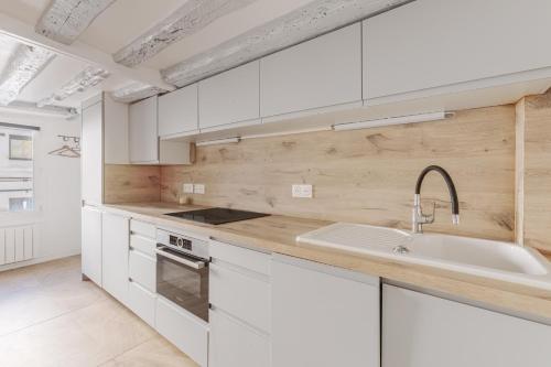une cuisine avec des armoires blanches et un évier dans l'établissement Apartment Cosy 3P Quartier République, à Paris