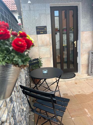 a table and a chair in front of a door with flowers at Zum Sterngässchen in Ludwigshafen am Rhein