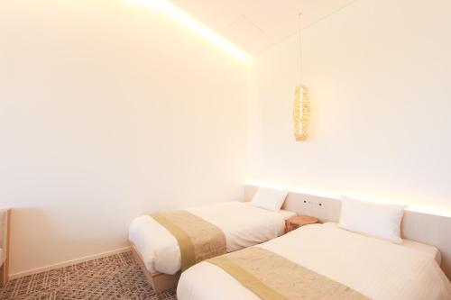 two beds in a room with white walls at HOTEL DO-YA Beppu in Beppu