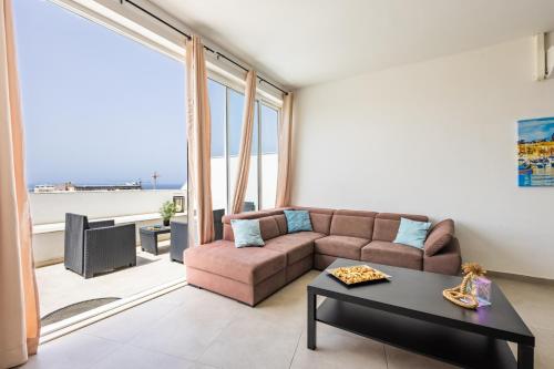 a living room with a couch and a table at Sea View & Private Terrace Near Promenade -Sleep 8 by QuickTrips in St. Paul's Bay