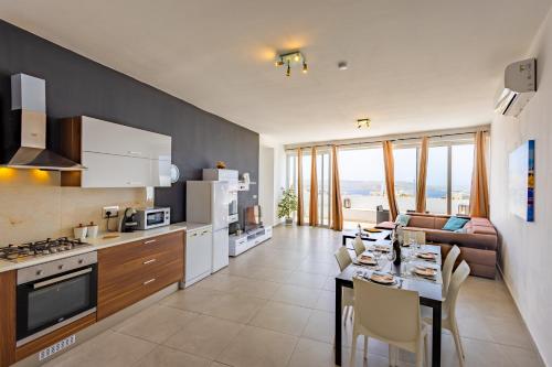 a kitchen and living room with a table and a couch at Sea View & Private Terrace Near Promenade -Sleep 8 by QuickTrips in St. Paul's Bay