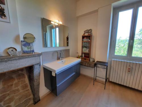 La salle de bains est pourvue d'un lavabo, d'un miroir et d'une cheminée. dans l'établissement La Maison Bleue Ancienne Ecole, à Sarrogna