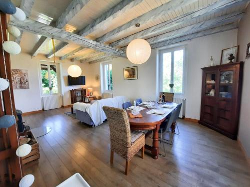 une salle à manger avec une table et un salon dans l'établissement La Maison Bleue Ancienne Ecole, à Sarrogna