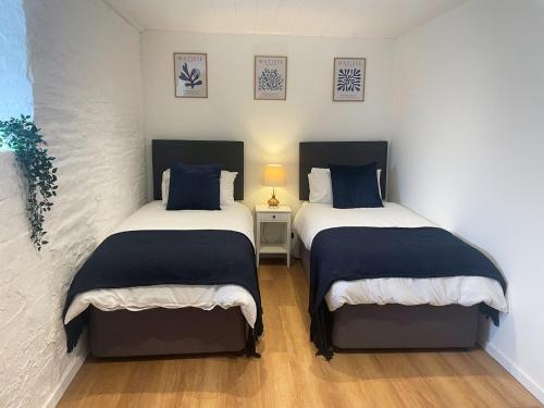 LlechrydにあるThe Granary, Cilbronnau Farm, Cardiganのベッドルーム1室(青と白のシーツが備わるベッド2台付)