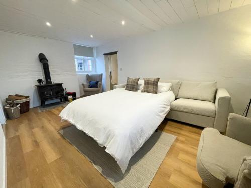 a bedroom with a white bed and a couch at The Granary, Cilbronnau Farm, Cardigan in Llechryd