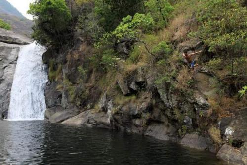 a person standing near a waterfall next to a body of water at Mount Mulanje Stopover in Peremwe