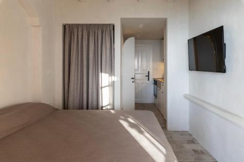 a bedroom with a bed and a flat screen tv at Om Living Pelion in Agios Dimitrios