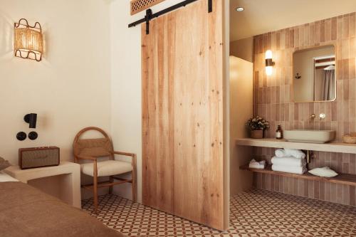 a bathroom with a wooden door leading to a sink at Nomad Hotel & Spa Altea in Altea