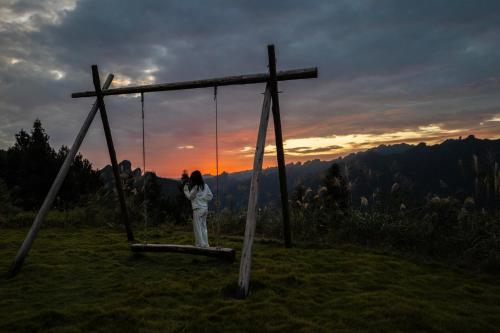 a woman sitting on a swing in front of a cross at BZIKA Wonderland Retreat--Zhangjiajie National Forest Park Store in Zhangjiajie