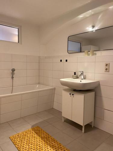 a bathroom with a sink and a tub and a mirror at Großzügiges 1 Zimmer-Apartment mit Badewanne in Pirna